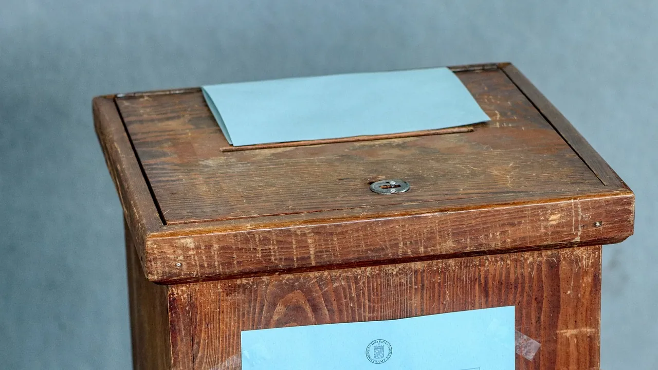 Urne de bois, un bulletin plié posé sur le couvercle